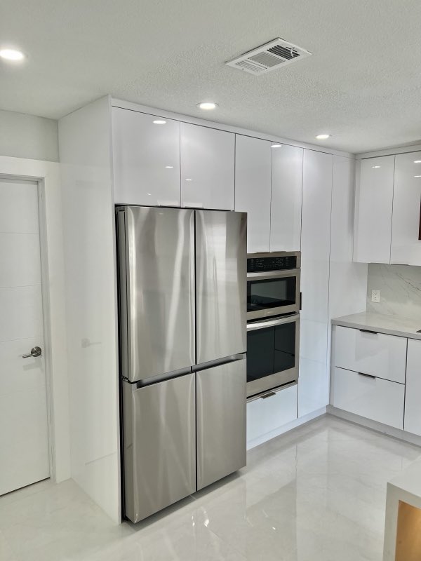 Clean white kitchen build with tall cabinetry and stainless appliances